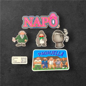 Pack STICKÔ N°1, assortiment de six autocollants Napô, présentant des personnages emblématiques dans différents styles et finitions.